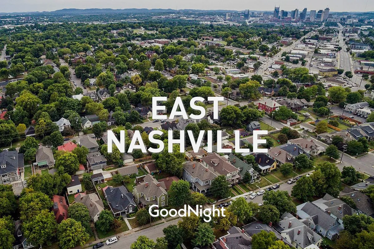 This view captures a vibrant Nashville neighborhood with residential houses, lush tree canopies, and the city skyline in the background. The atmosphere is welcoming and lively, suggesting community gatherings and local events.